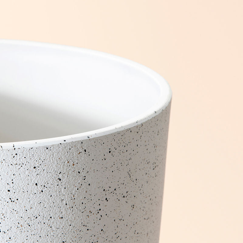A close-up of the white planter, showing its speckled pattern and smooth rim feature.