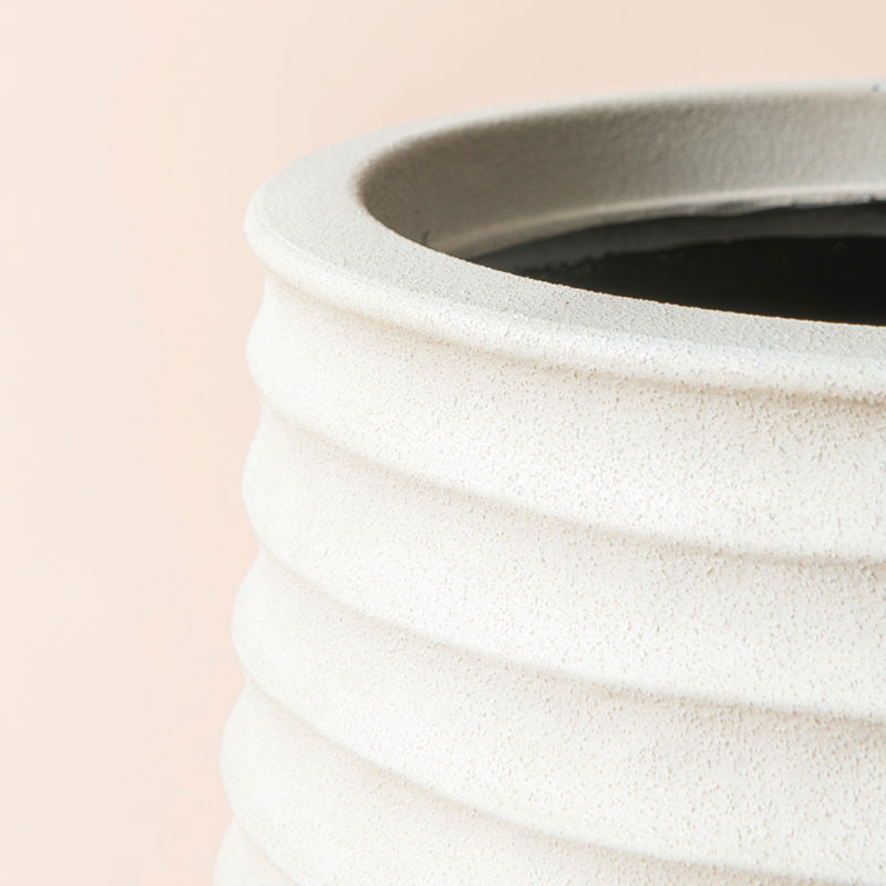 A close view of sand beige plastic planter, showing its uncluttered curve patterns and grainy surface. 