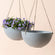 A set of two weathered gray hanging planters, made from recyclable plastic and natural stone powders.