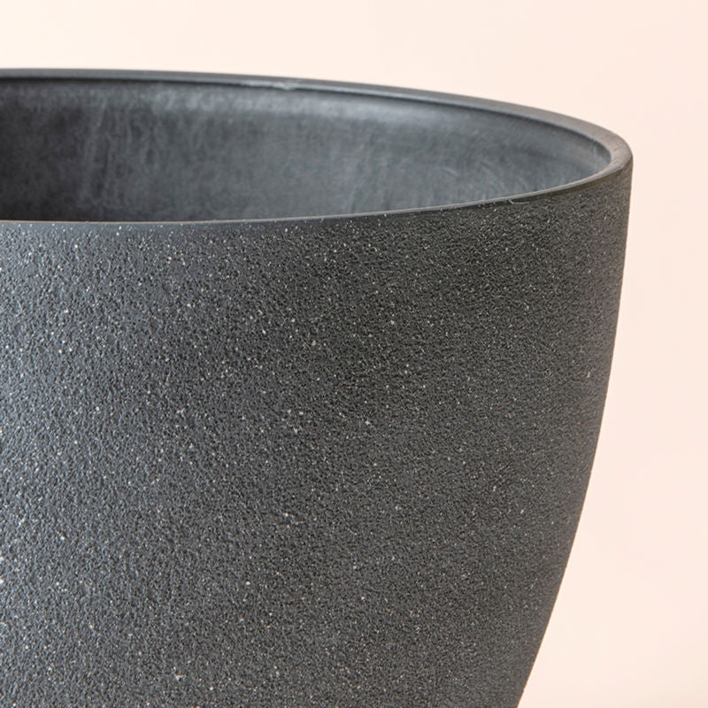 A close up of weathered gray planter, showing its concrete texture and grainy exterior.