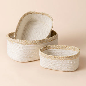 A set of three white rope and corn skin baskets. Two baskets are stacked and placed next to the larger one.