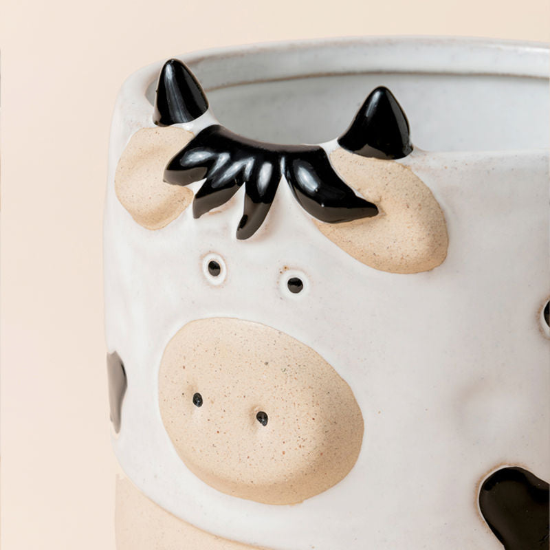 A close view of a white cow planter, showing its animal-like design and handmade texture. 