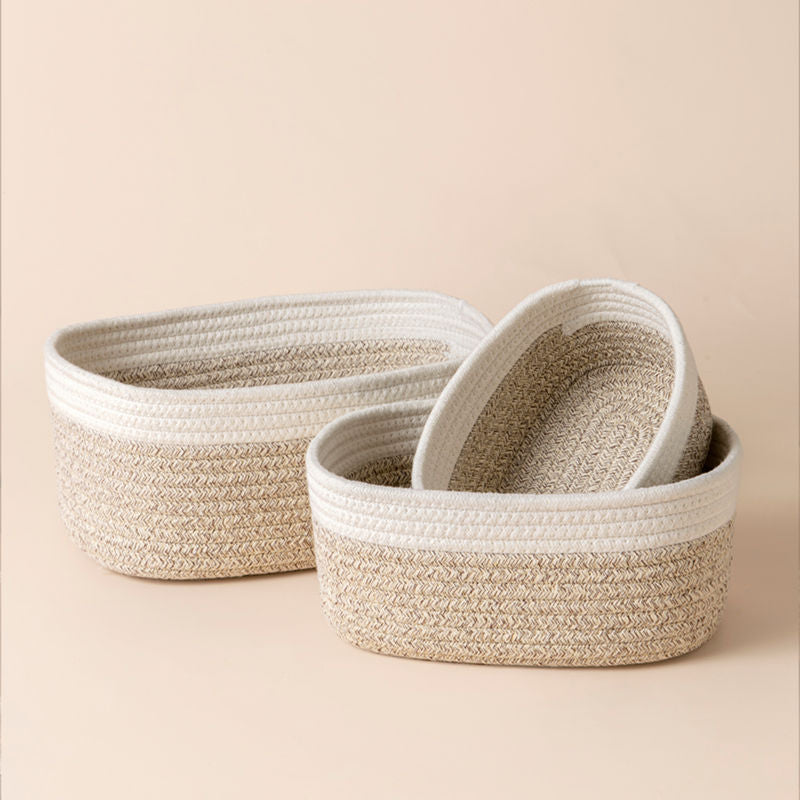 A set of three white and desert rope baskets in different sizes. Two baskets are stacked and placed next to the large one.