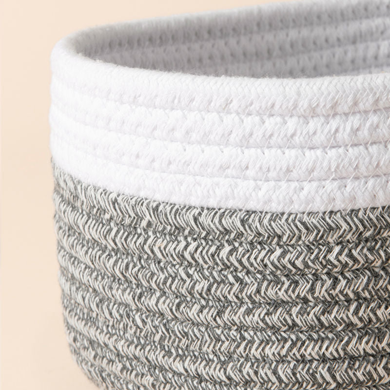 A close up of white and gray rope basket, showing its fabric texture and dual-colored design.