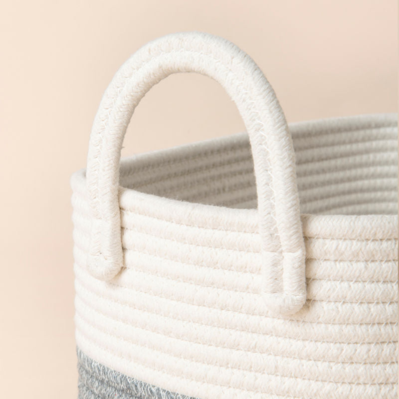 A close up of white and gray rope basket, showing its arched handle and soft texture.