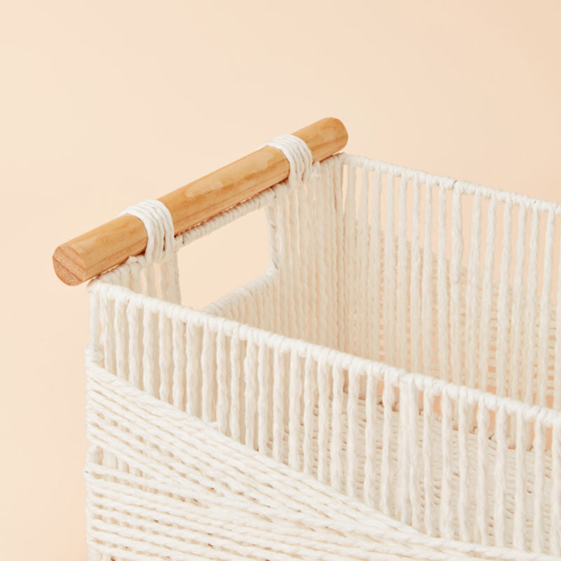 A close up of white paper rope basket, showing the dowel-style handles on the side of its body.