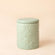 The wooden pine scented candle, in a jadeite pottery jar which is covered with sculpted daisy reliefs.
