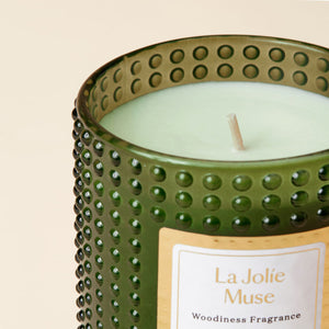 A close-up of Woody and Sandalwood candle, showing its single cotton wick and yellow label.