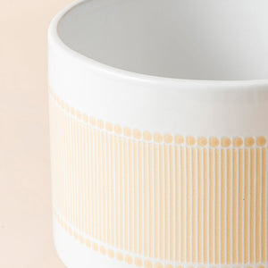 A close up of yellow beige ceramic planter, showing its boho-chic pattern and fully glazed body.