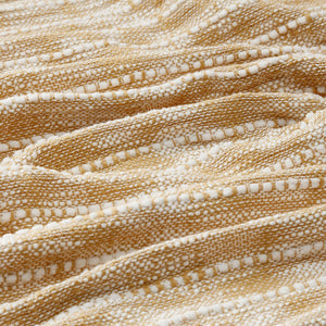 A close-up of the white and yellow throw blanket, shows the loose weave texture.、